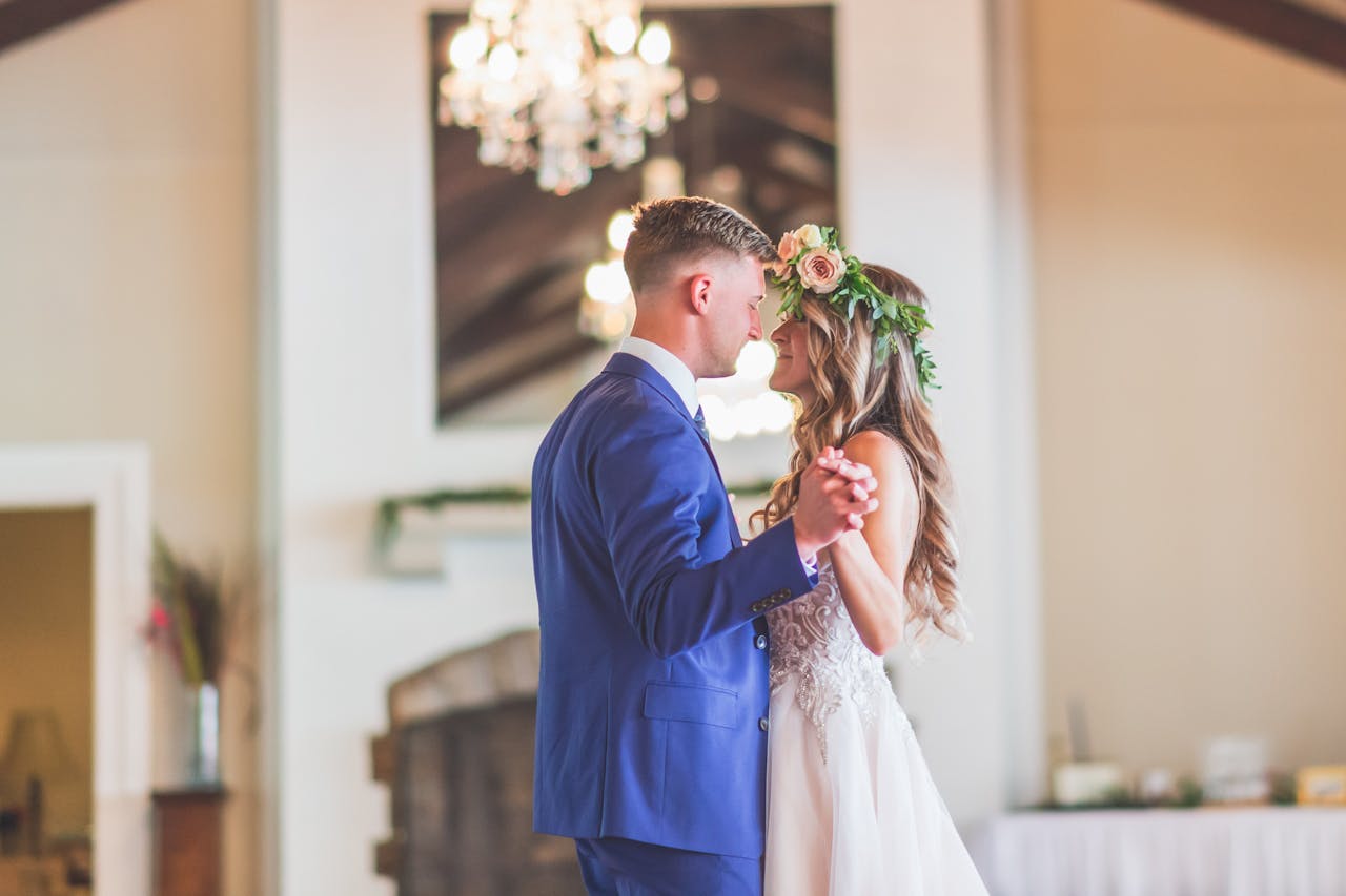 A newlywed couple shares a romantic first dance indoors, capturing the joy of their wedding day.